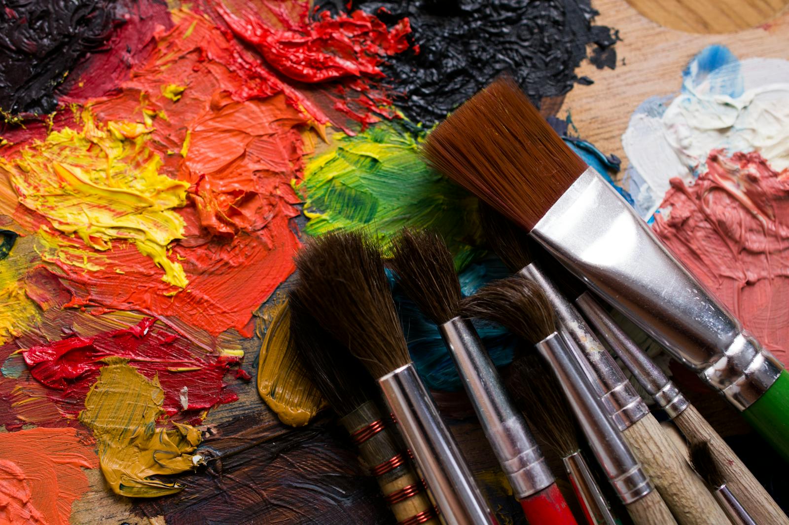 Colorful palette with vibrant paints and brushes ready for a creative painting session.