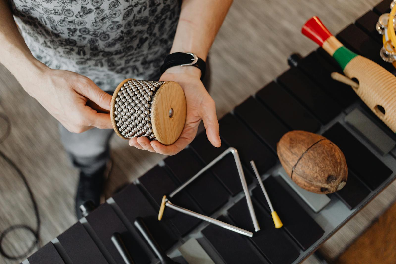 Close-up view of a musician holding a cabasa, showcasing percussion instruments.