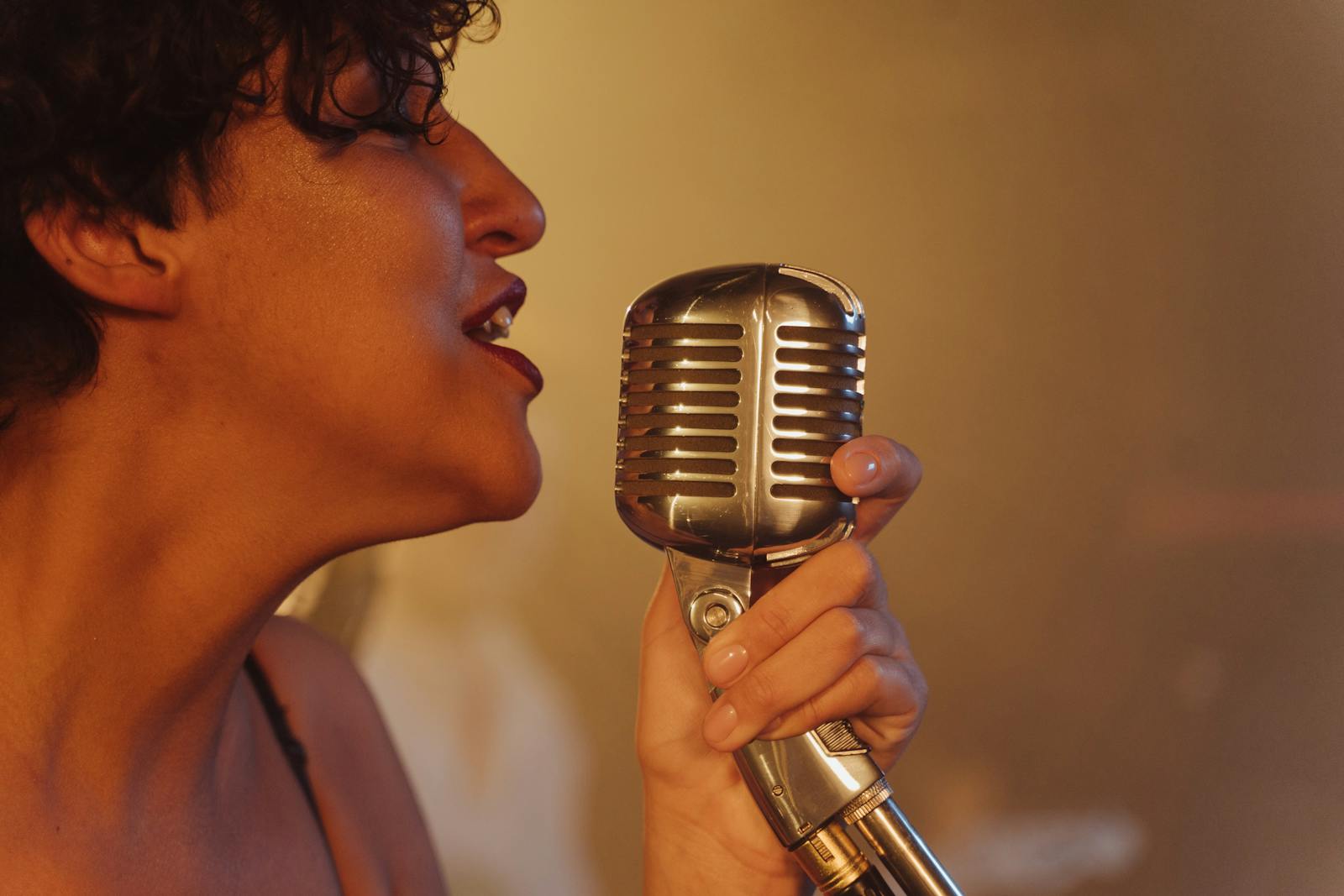 Close-up of a female jazz singer passionately performing with a vintage microphone.